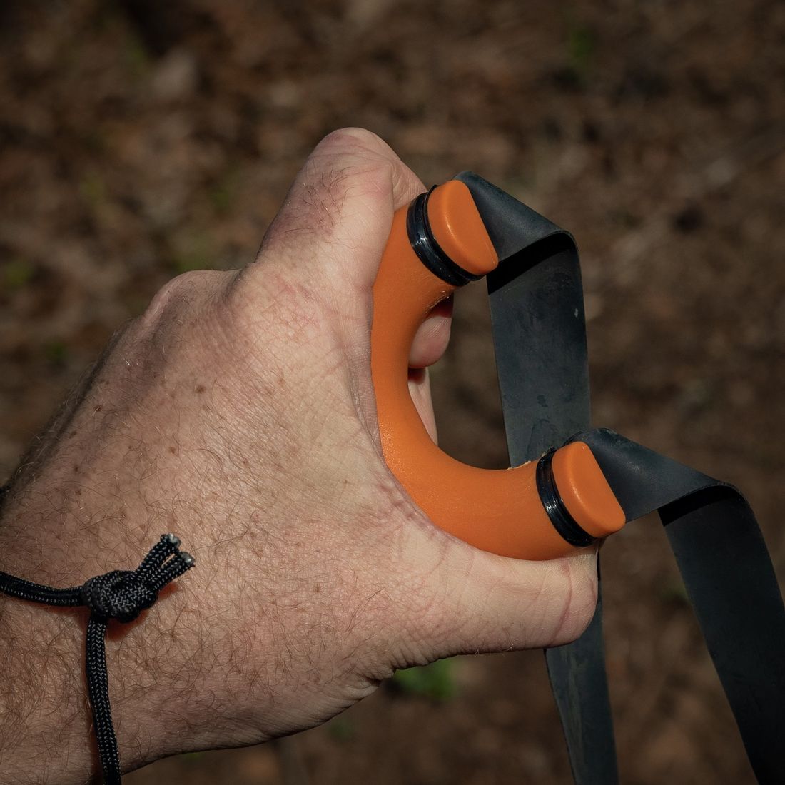 Hand wrapped around the round handle of an orange Sparrow